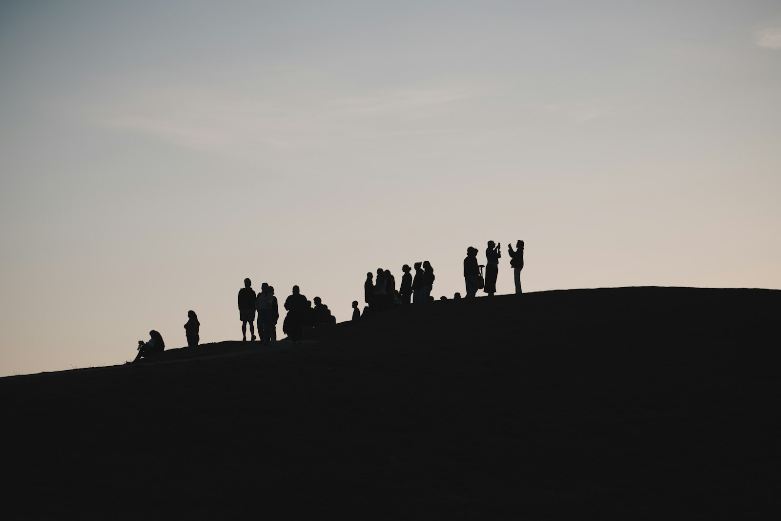Photo by Joey Zhou People silhouetted on a hilltop against a pale sky